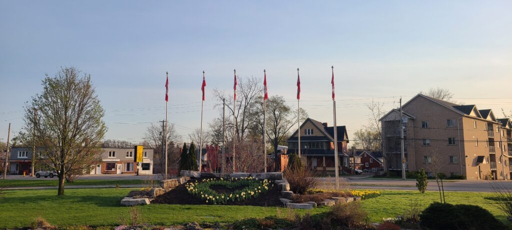 six flag poles with a garden at their base, planted with tulips in the shape of a heart